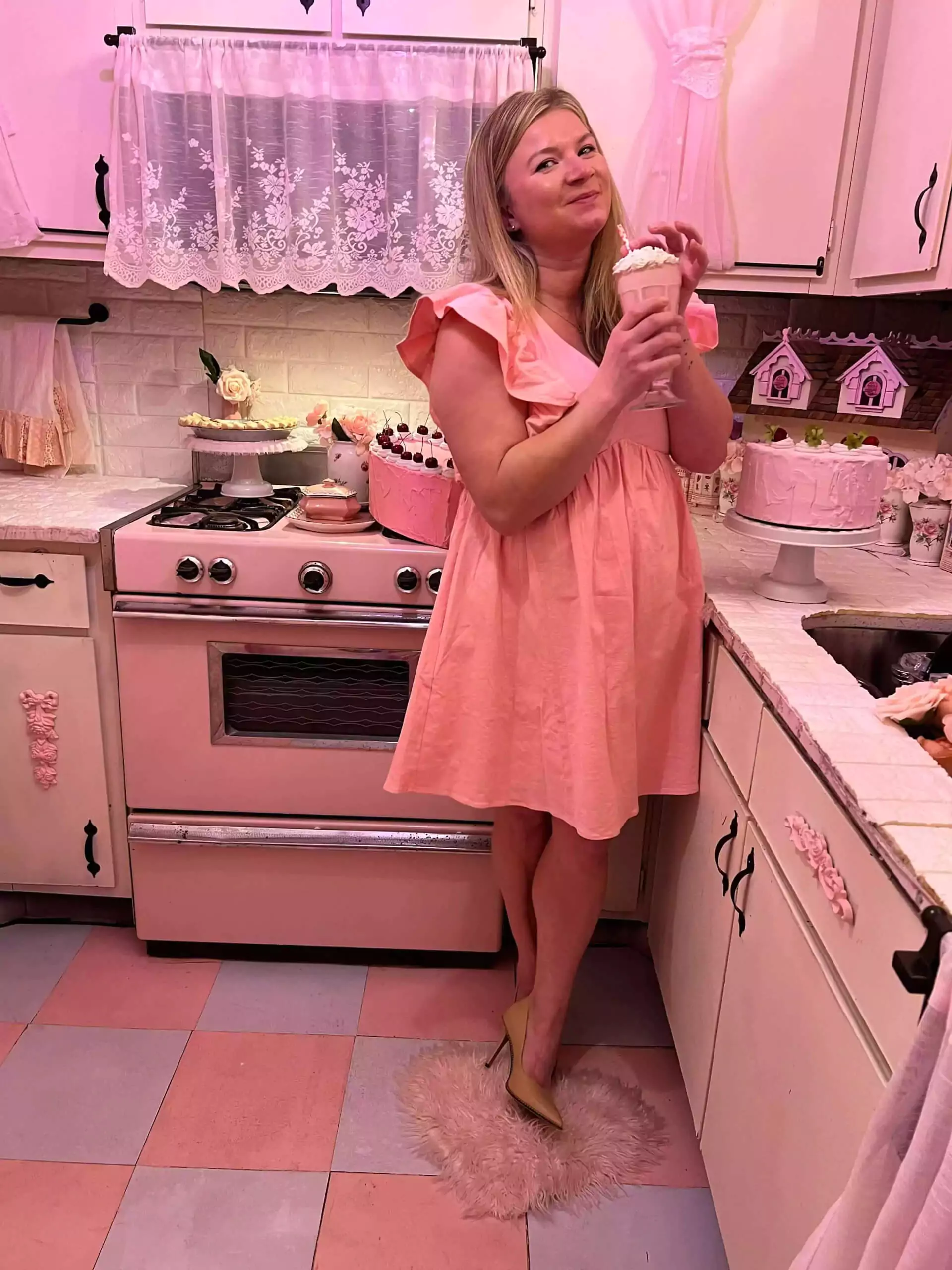 The Dallas Dollhaus Photography Studio Katie wearing pink dress and nude heels in pink kitchen